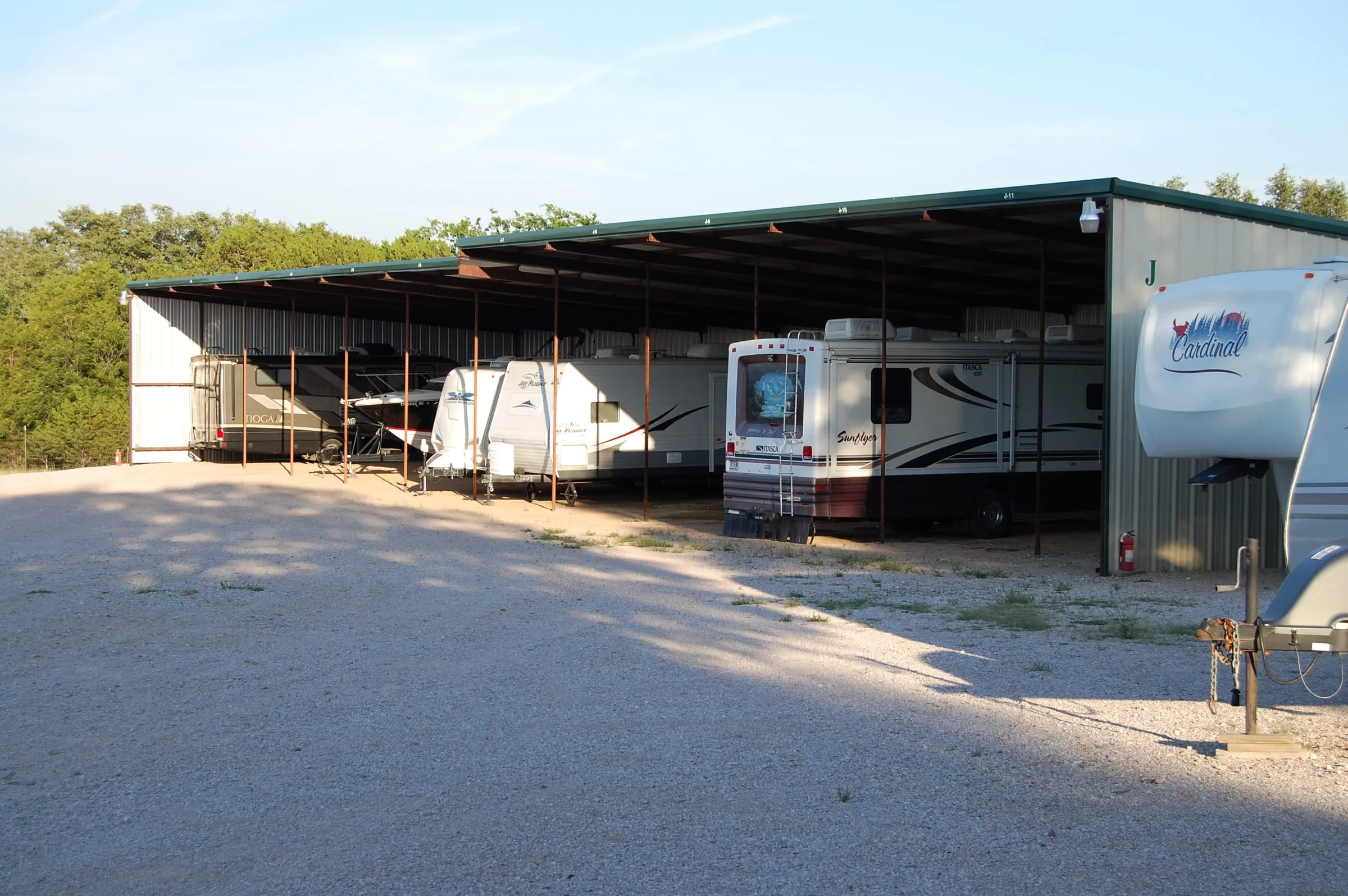 RV storage canopy with green trim sheltering motorhomes.
