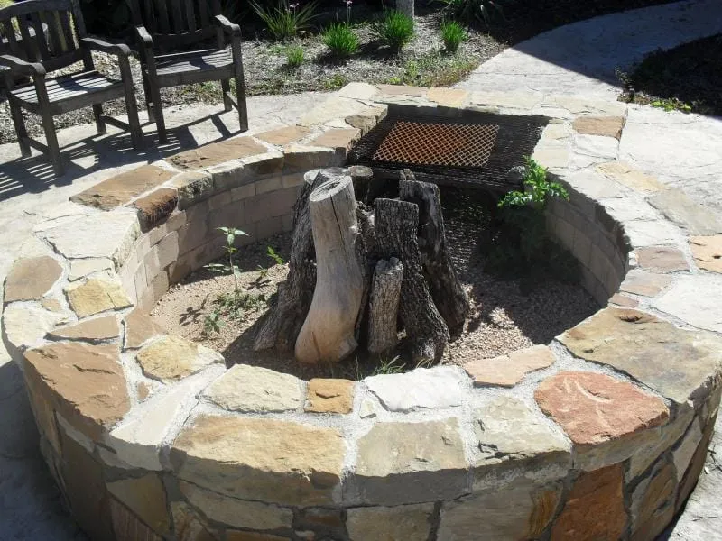 Custom stone fire pit in a landscaped back yard.