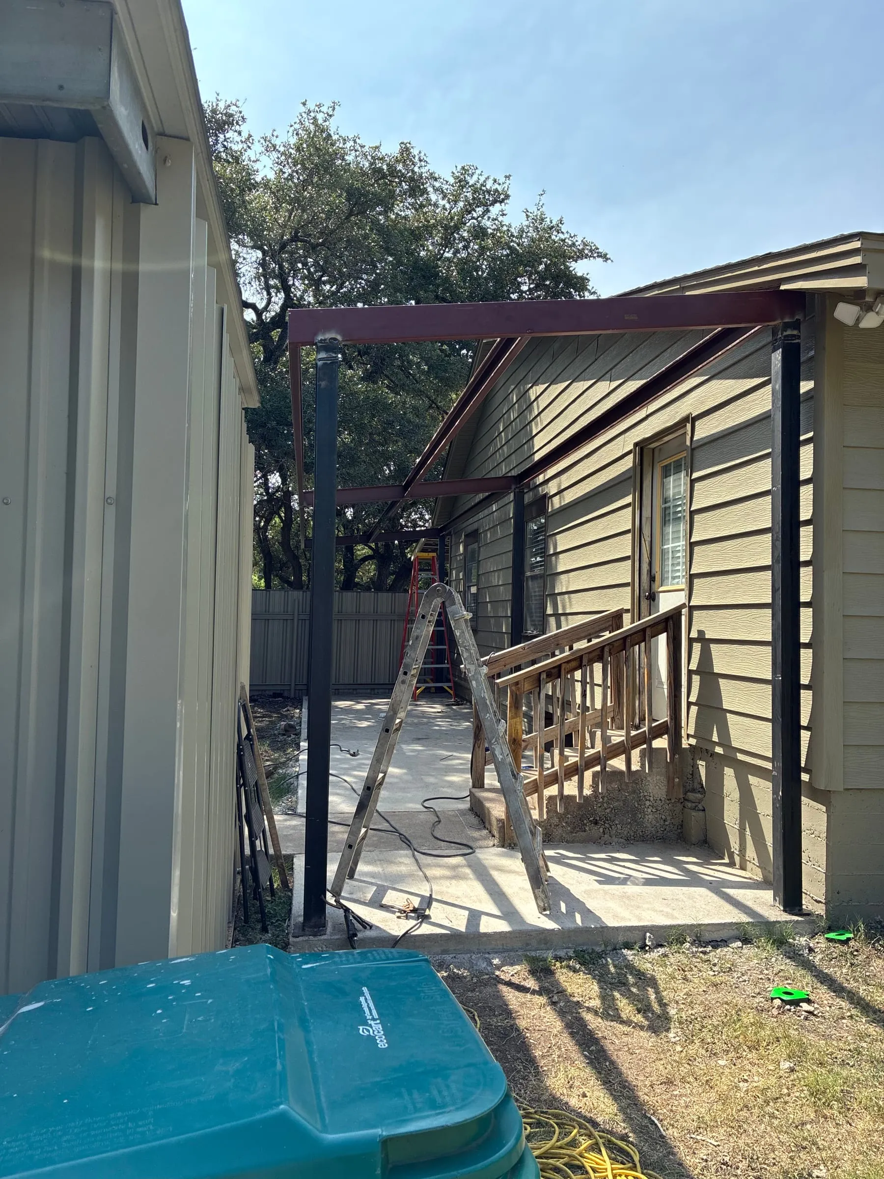 Patio-cover steel framing aligned over the existing entry steps.