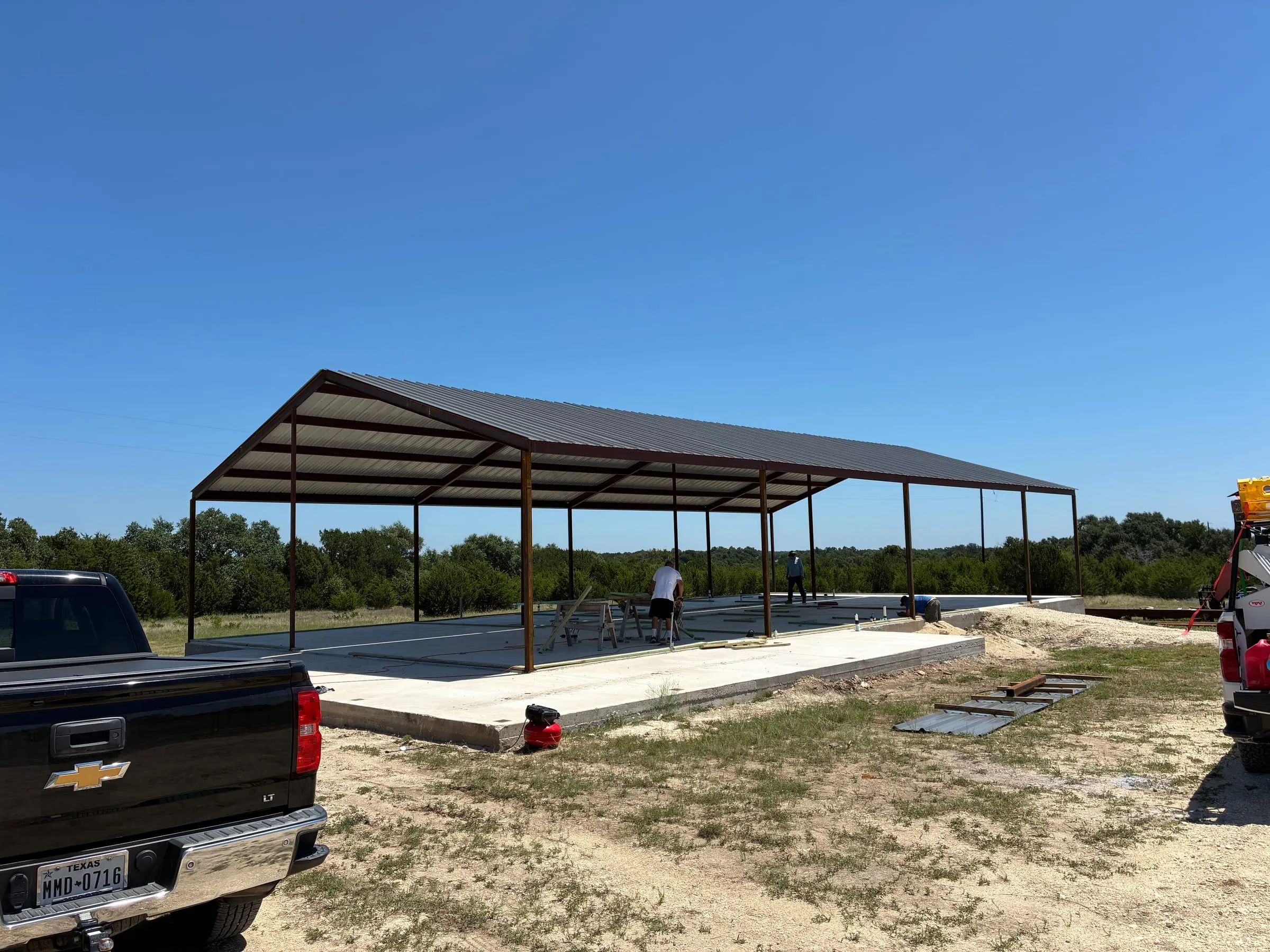 Wide view of the finished steel frame and roof over the shop slab.
