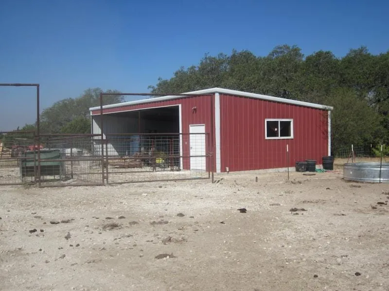 Red livestock shelter with pen fencing.