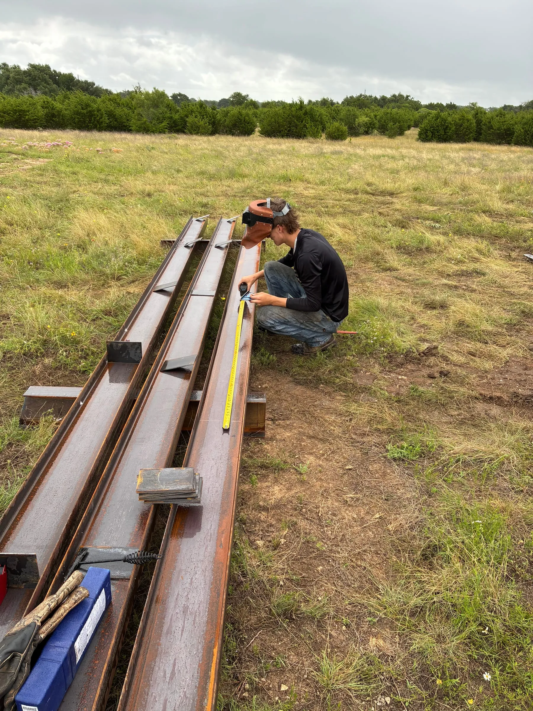Worker marks a connection point on stacked structural steel.