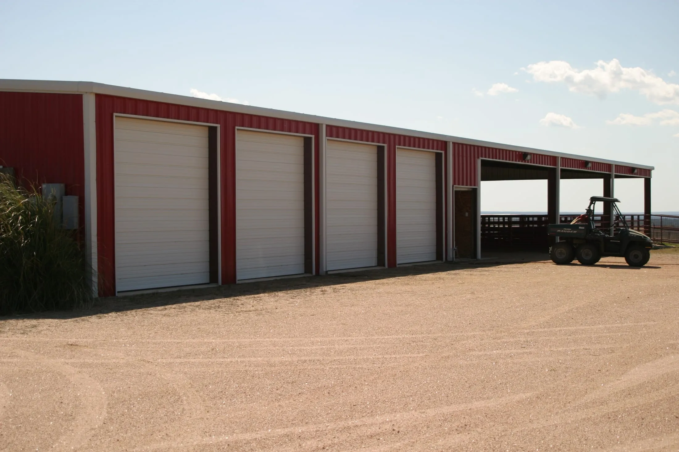 Commercial metal storage building with red trim and multiple roll-up doors.